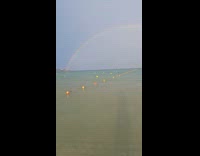 Guy on beach while raining see rainbow