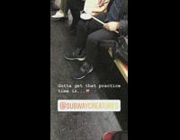 Guy practices the drums with drum pad on lap on subway