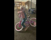 Little girl tries to ride pink tricycle  bike and falls over