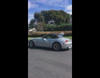 Guy BMW z4 coupe convertible driving with surfboard out of window