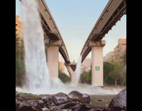 Artificial waterfalls on side of brown bridge 