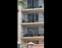 Woman in bikini poses with baby on the chair at the balcony