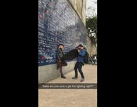 Girl writing blue wall holding light reflector 