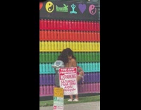 Girl poses in front of rainbow wall 
