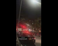 People on sidewalk watch person on roof 