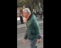 Man in white coat raise foot sideways on the street