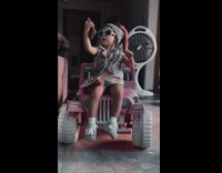 Slowmo of baby toddler girl in sunglasses and outfit on toy jeep
