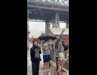 Three people cheer bikers while it rain