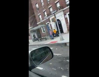 Man in yellow rides motorcycle on sidewalk