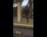 Man puts one leg high up on cement pillar and stretches legs at subway station