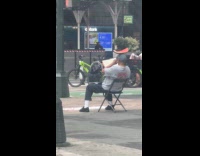 Man sitting reading book with watermelon slice on head