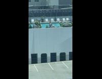 Woman in white bikini poses on the rooftop wall