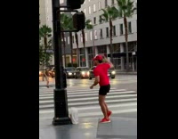 Man in red top and at tiktok in front of the lamppost