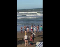 Group of people dances together at the windy beach 