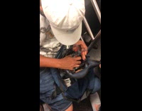 Guy cuts inside plastic ziploc bag with gray red scissors on subway train