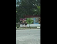 Shirtless guy arms sideward tulum sign street