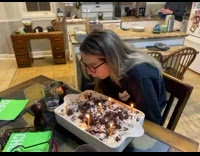 Woman trying to blowout candles but hair catches fire