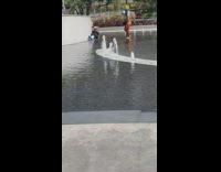 Woman black top with mermaid fin poses at the water fountain