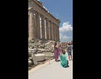 Woman in violet dress poses near the ruins