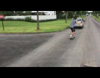 Guy holds onto back of car with rope and rides skateboard then falls down next to tree