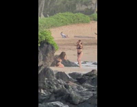 Woman in black bikini poses at the beach shore