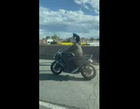 Man drives motorcycle with stuff toy on his helmet