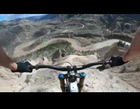 Guy rides bicycle down steep canyon mountain 