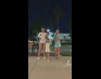 Kid Dances with Two Ladies on a Sidewalk
