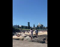 Man in striped shirt poses at the beach rocks