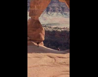 Girl sit under stone arch waves upward