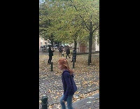 Woman in winter coat throws dried leaves in the air