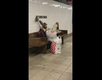 Man lays down and stretches his legs on subway station bench