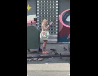 Random woman stands at sidewalk petting pigeons