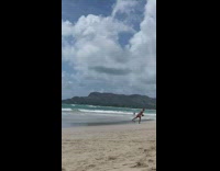 Woman black bikini with rubber band lifts dumbbell at the beach