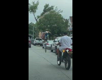 White shirt guy rides unicycle down street 
