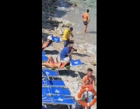guy white pants lays on beach rocks