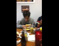 Guy pans camera at friends eating breakfast and shows friend sucking finger