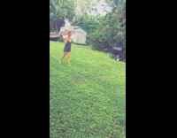Lady holding umbrella walks barefoot across grass