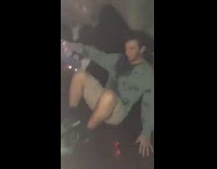 Guy in green sweatshirt falls down trying to limbo 