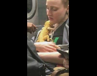 Woman cuddles with yellow lizard reptile on her chest on subway train