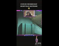 Husband streams with wife in a pink range helmet in the background