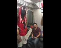 Black spiderman with beggar sign does shaka hand sign at camera on subway train
