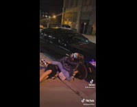 Girl jumps on guy and he falls onto black car 