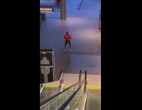 Man jump squats at bottom of escalator 