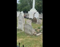 Girl squats on grass in graveyard 