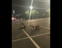 Guy wheelies on motorcycle, scrapes back on concrete and spins out of control in parking lot