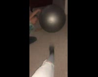 Girl kicks silver exercise ball into little boy