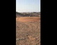 guy on hill jumps over fence lands on dirt