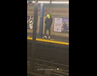Guy wearing yellow ski mask on subway platform dances to music
