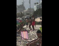 Couple dance slap thigh at crowded beach 